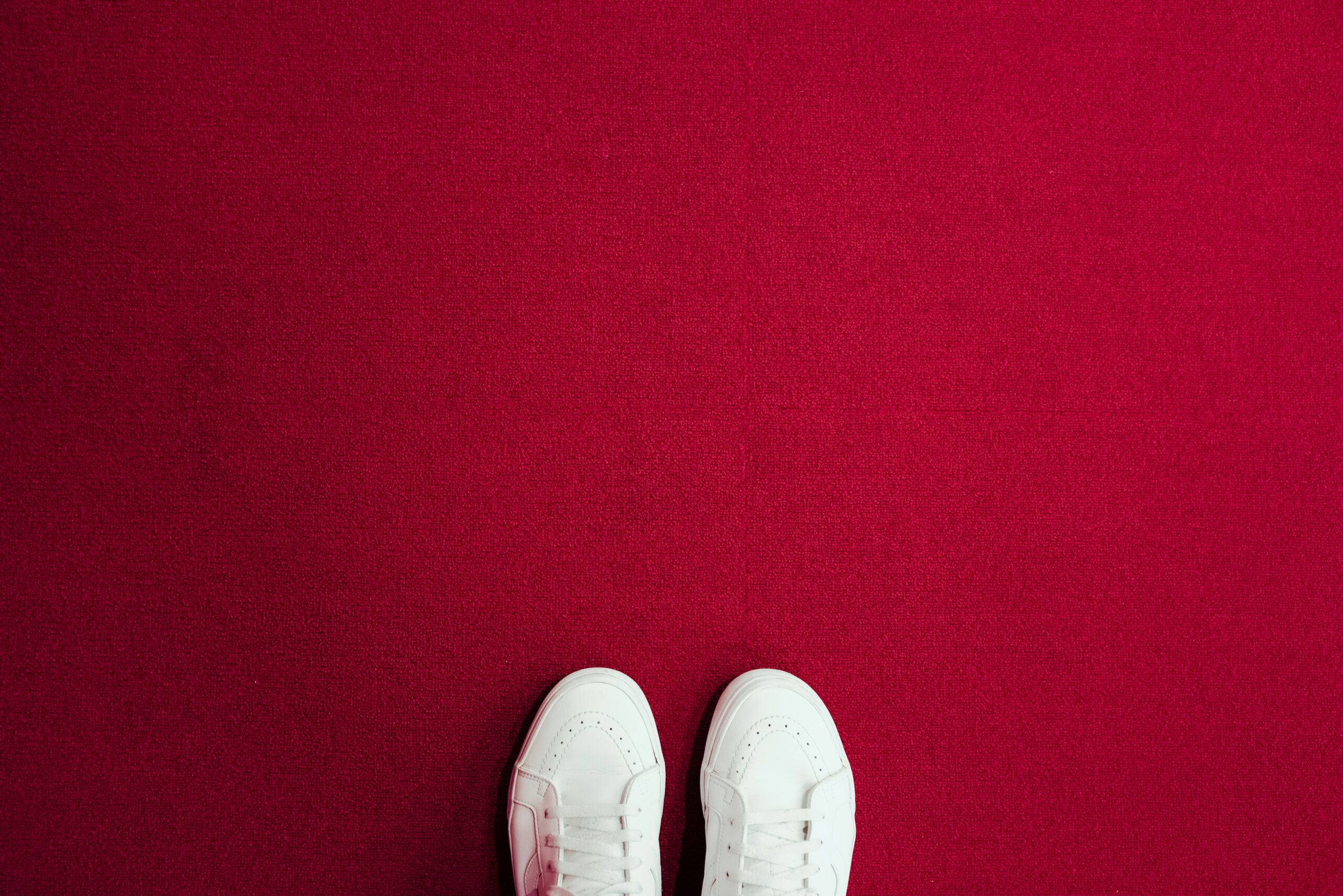 white trainers from above on a red flooring.